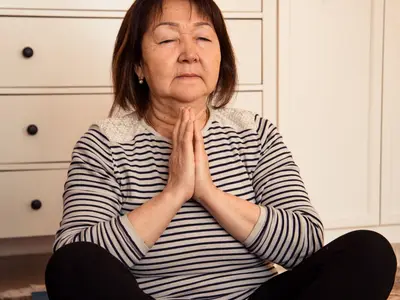 An older woman meditates seated on the floor.