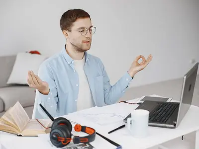 A man pauses to meditate at his desk.